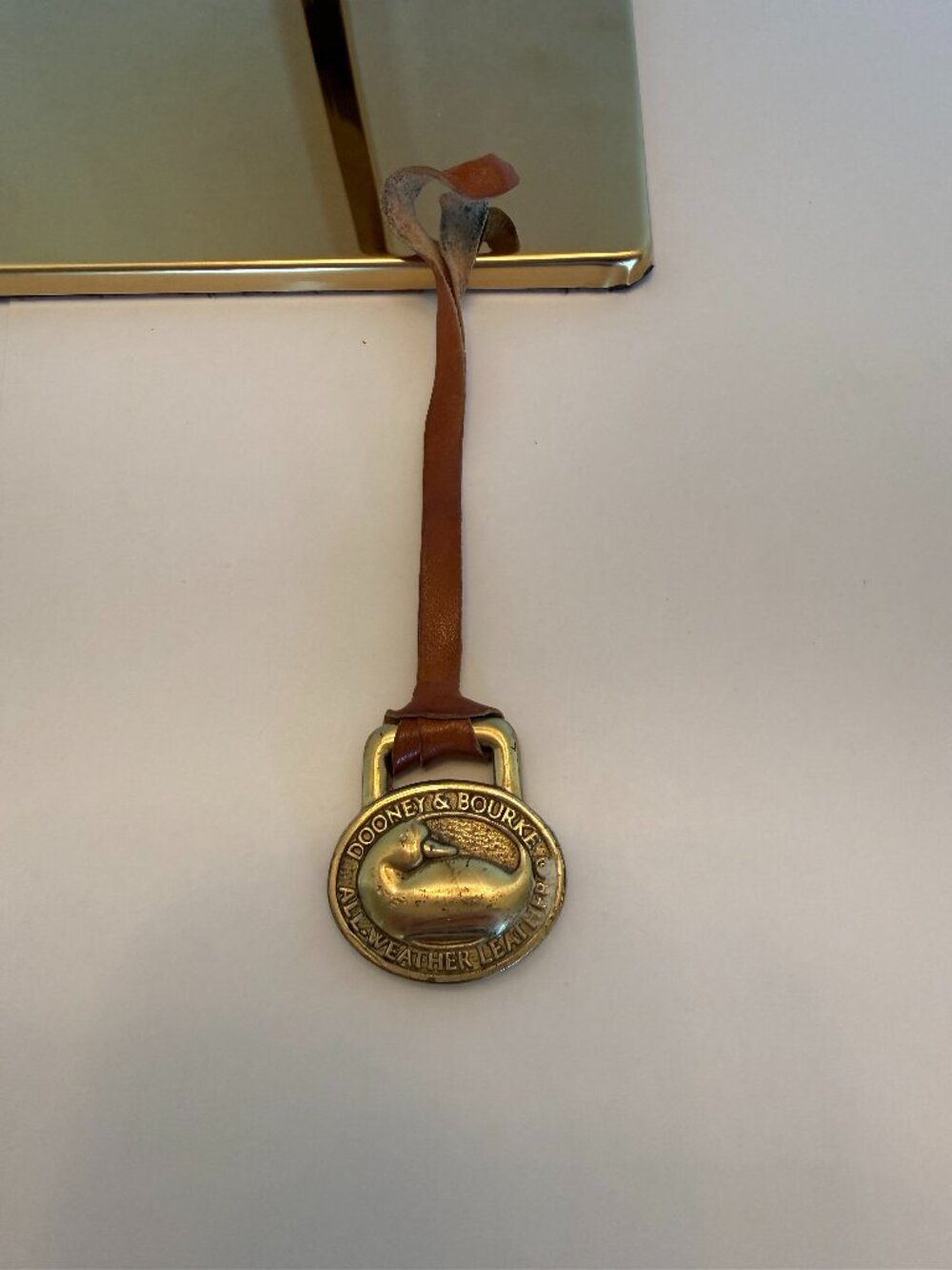Dooney & Bourke Brass/Leather hangtag